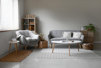 Interior of modern living room with grey sofa and table near window