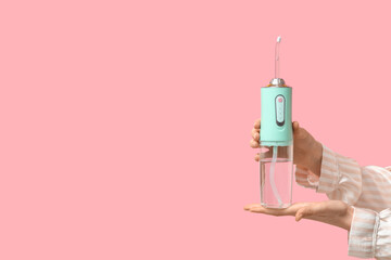 Female hands with oral irrigator on pink background