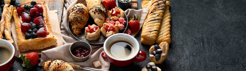 Table with various pastries and coffe cups.