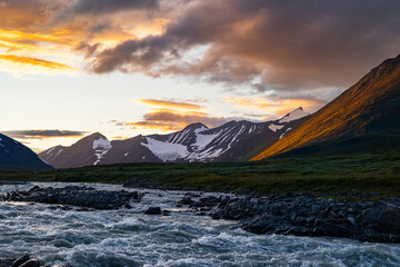 A wild, turbulent mountain river in the Sarek National Park, Sweden. A summer scenery with water in...