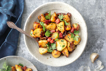 Sautéed potatoes with garlic and parsley, presented in an organic dish on a light background with...