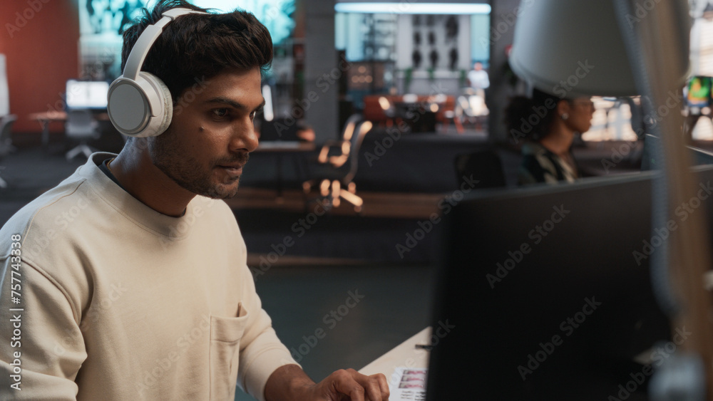 Poster Male Indian Game Programmer Coding On Desktop Computer In Game Design Studio Diverse Office. Focused Man Writes Lines Of Code, Does Gameplay Engineering For New Immersive 3D Survival Video Game