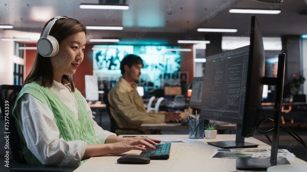 Poster Female Asian Game Programmer Coding On Desktop Computer In Game Development Studio Diverse Office. Focused Woman Writes Lines Of Code, Does Gameplay Engineering For New Immersive 3D RPG Video Game