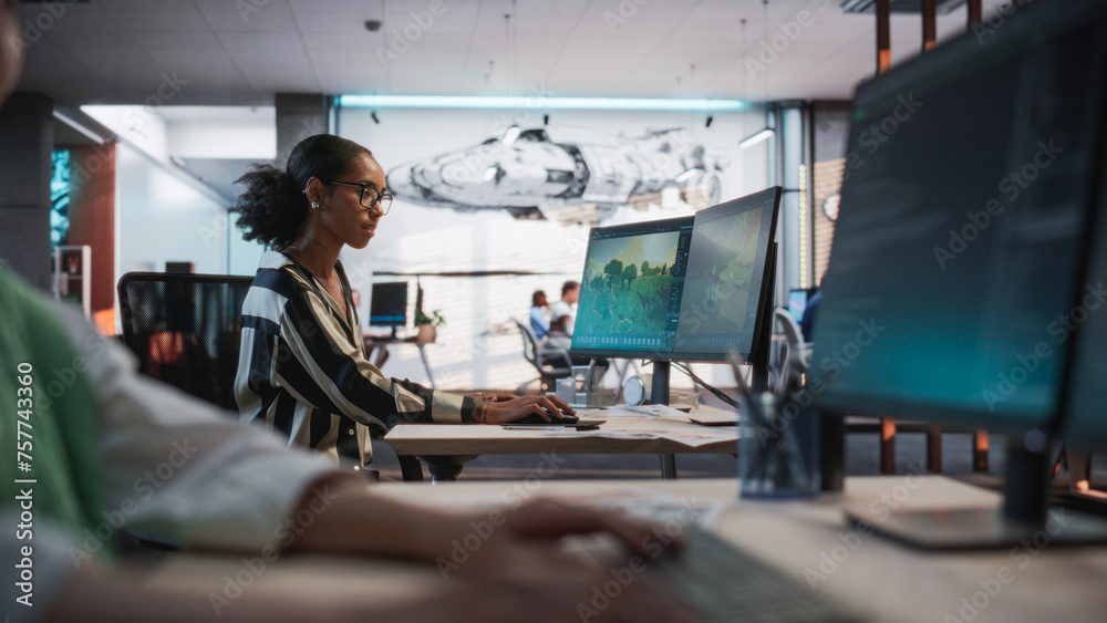 Poster Black Female Game Developer Using Desktop Computer With 3D modelling Software And Talking to Asian Female Project Manager in Game Design Studio Office. Two Diverse Colleagues Discussing New RPG Game