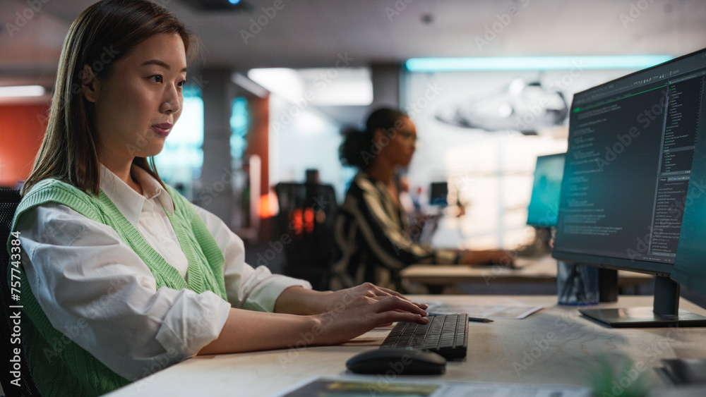 Aufkleber Female Asian Game Programmer Coding On Desktop Computer In Game Development Studio Diverse Office. Focused Woman Writes Lines Of Code, Does AI Engineering For New Immersive 3D Survival Video Game