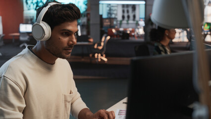 Male Indian Game Programmer Coding On Desktop Computer In Game Design Studio Diverse Office....