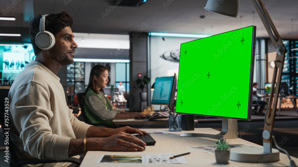 Aufkleber Indian Male Game Designer Using Desktop Computer With Green Screen Chromakey on Display, Designing Immersive World In 3D Modelling Software For New Video Game. Man Working In Game Development Office