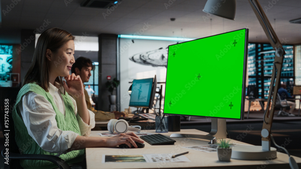 Fototapete Female Asian Game Programmer Coding On Desktop Computer With Green Screen Chromakey On Display In Game Design Studio Office. Stylish Woman Does Gameplay Engineering For New Immersive 3D RPG Video Game