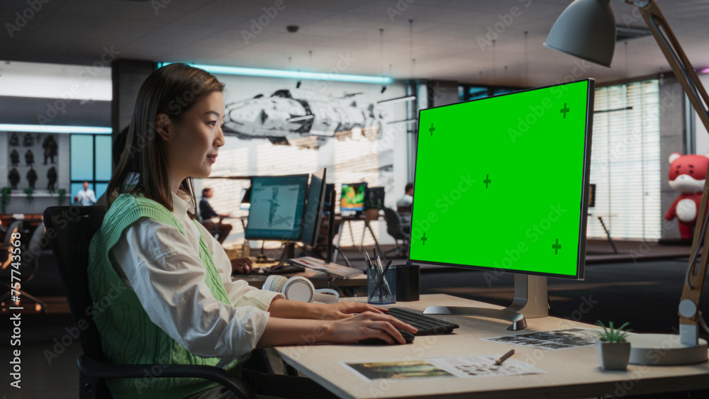 Fototapete Female Asian Game Programmer Coding On Desktop Computer With Green Screen Chromakey On Display In Game Design Studio Office. Stylish Woman Does Gameplay Engineering For New Immersive 3D RPG Video Game