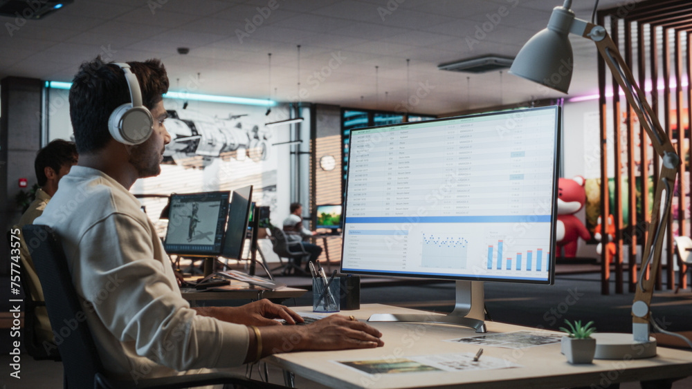 Poster Indian Male Manager Using Desktop Computer With Analytics Software wth Financial Reports. Man Working In Game Development Company Diverse Office