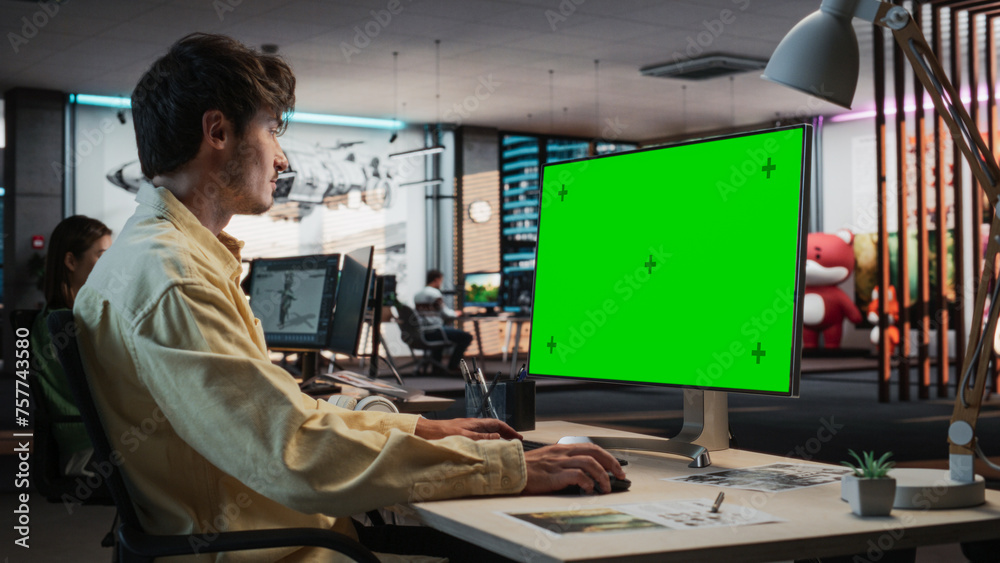 Leinwandbilder Portrait of Creative Caucasian Man Sitting at a Desk Using Desktop Computer with Mock-up Green Screen Chromakey. Male Concept Artist Working in Game Design Startup Office, Creating Immersive Gameplay.