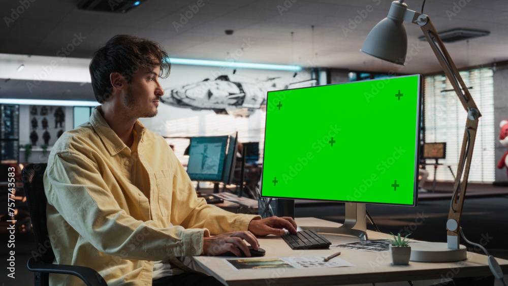 Leinwandbilder Caucasian Man Using Desktop Computer with Mock-up Green Screen Chromakey. Male Concept Artist Working in Game Design Startup Diverse Office, Creating Immersive Gameplay For New Adventure Video Game.