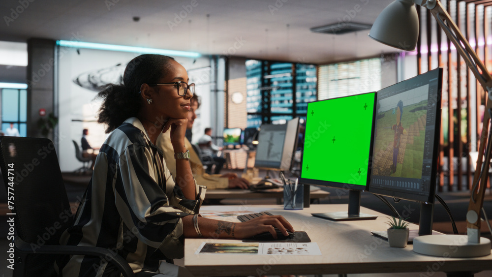 Aufkleber Female Black Game Designer Using Desktop Computer With Green Screen Chromakey on Display, Designing Characters In 3D Modeling Software For Survival Video Game. Woman Working In Game Development Office