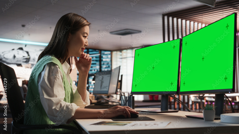 Poster Female Asian Game Designer Using Desktop Computer With Green Screen Chromakey on Display, Designing Characters In 3D Modeling Software For Survival Video Game. Woman Working In Game Development Office