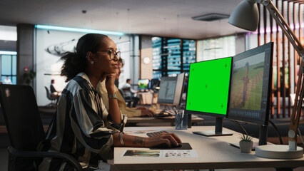 Female Black Game Designer Using Desktop Computer With Green Screen Chromakey on Display, Designing...