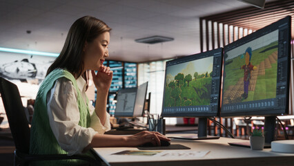 Female Asian Game Designer Using Desktop Computer, Designing Unique World And Characters In 3D modelling Software For RPG Video Game. Woman Working In Diverse Game Development Studio Office.