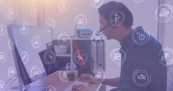 Image of network of digital icons over businessman using phone headset and computer in office - Powered by Adobe