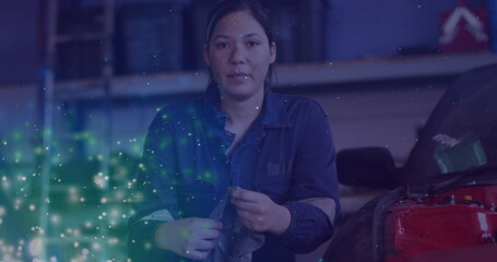 Image of glowing lights over caucasian female car mechanic in workshop