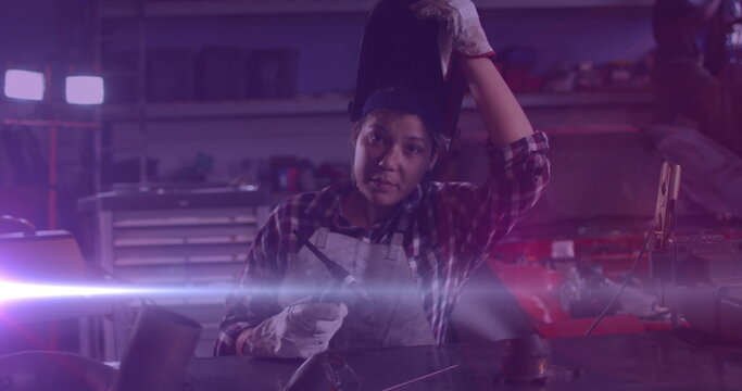 Image of glowing light over caucasian woman working in workshop