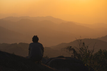 landscape and travel concept with solo freelancer man relax at top of mountain and sunset with layer of mountain