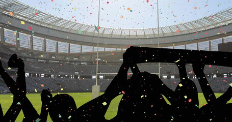 Colorful confetti falling against silhouette of fans cheering and sports stadium in background