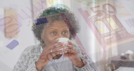 Image of senior woman drinking tea over euro currency bills