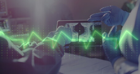 Image of cardiograph over diverse surgeons using tablet at hospital