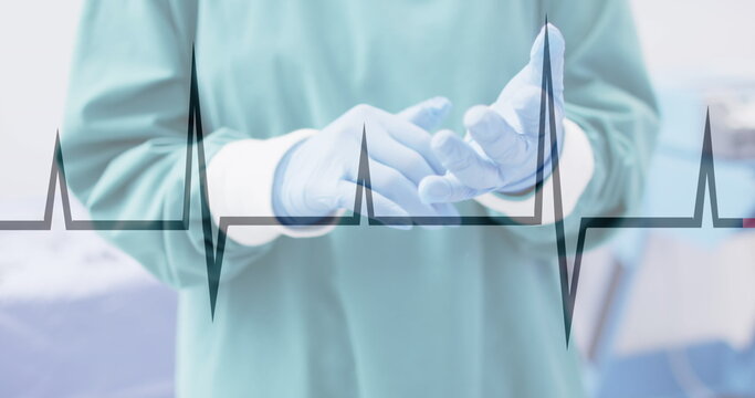Image of cardiograph over surgeon wearing medical gloves at hospital