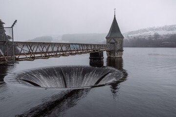 the plug hole on the Pontsticill Reservoirshowing the valve tower and the convex-sided large funnel outflow. Taken in a light snow.