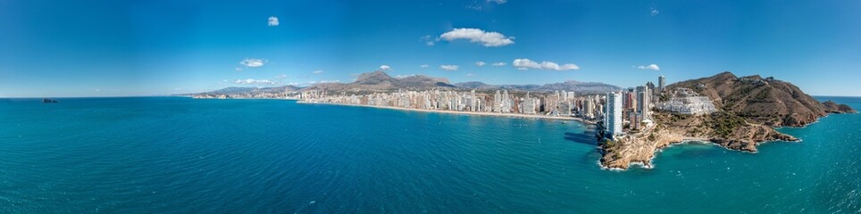 Extremely wide aerial drone photo of the norther part of Benidorm in Spain showing the Cala Almadraba Beach and the main Llevant beach on a sunny day in the summer time. - obrazy, fototapety, plakaty