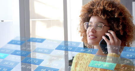 Data processing on interface over biracial casual businesswoman talking on smartphone at office