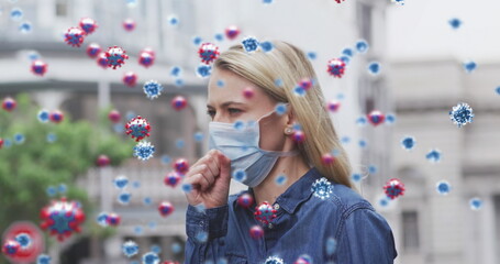 Image of virus cells over caucasian female wearing face mask coughing