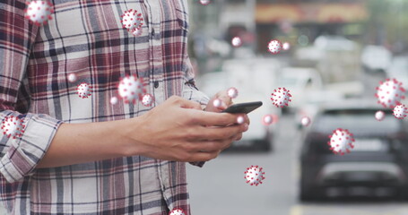 Image of world map and statistic data over latin male wearing face mask, using smartphone
