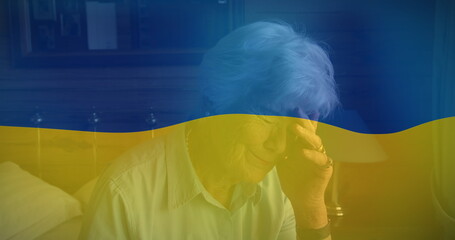 Image of flag of ukraine over senior caucasian woman crying
