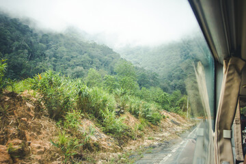 Bus ride through the mountains. Transportation in Vietnam background. Foggy weather. Dense forest...