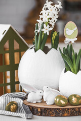 Happy Easter. A spring hyacinth flower in an egg-shaped vase, Easter bunnies and eggs with a golden...