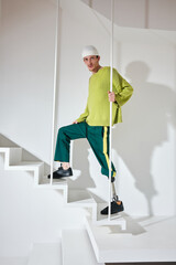studio portrait of successful happy  tattooed one-legged disabled young man with amputee leg with prosthesis fashionably dressed in bright colored youth street style clothes 