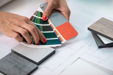 An interior designer meticulously curates color samples, including compact boards, for a harmonious...