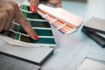 An interior designer meticulously curates color samples, including compact boards, for a harmonious...