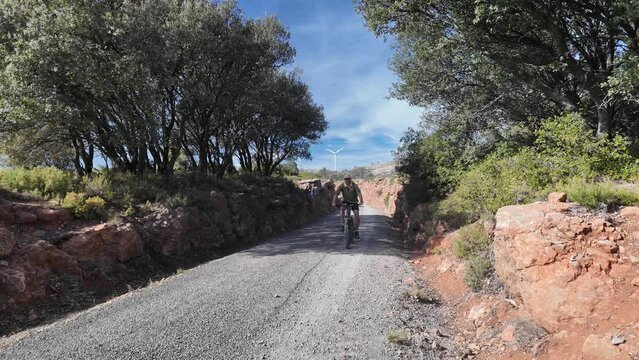 White european cyclist riding a  BTT bike in green way, Via Verde Ojos Negros, castellon, Spain. Frontal view, fixed camera. 4K 60FPS