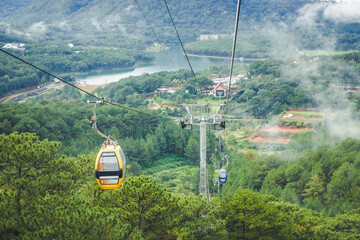 Da Lat in Vietnam cable car. Ropeway over tree tops forest. Foggy cloudy rainy day. Low season...
