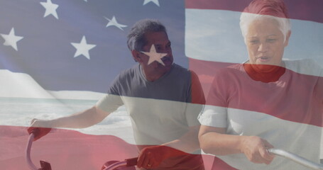 Image of flag of united states of america over senior biracial couple with bikes on beach