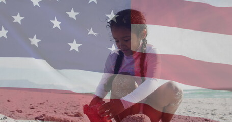 Image of flag of united states of america over biracial girl playing with sand on beach