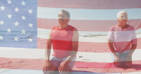 Image of flag of united states of america over senior biracial couple meditating on beach