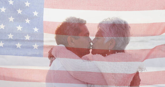 Image of flag of united states of america over senior biracial couple embracing on beach - Powered by Adobe