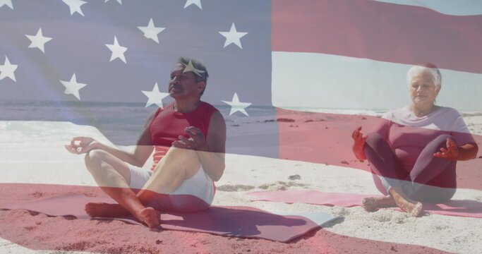 Image of flag of united states of america over senior biracial couple practicing yoga on beach
