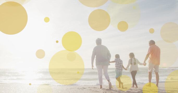 Image of holly text and light spots over biracial family at beach