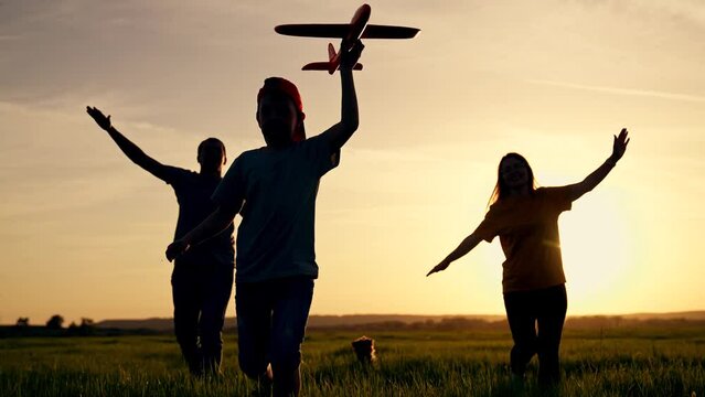 Happy family concept.happy children with their parents run across field at sunset with toy airplane.dream of flying and becoming pilot.family runs with toy airplane in nature. family weekend. teamwork