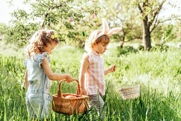 Easter egg hunt. Group Of Children Wearing Bunny Ears Running To Pick Up colorful Egg On Easter Egg Hunt In Garden. Easter tradition - 757786513