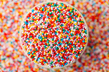 Confectionery sprinkles in bowl. Colorful background. Decoration for cake and bakery.
